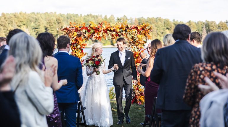 A bride and groom walking down the aisle after their lakefront wedding ceremony in Vermont.