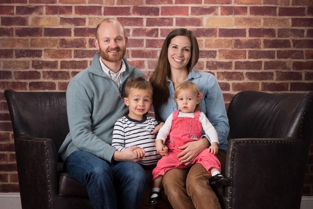 A happy family of four sitting on a leather chair during a session with a Vermont family photographer.