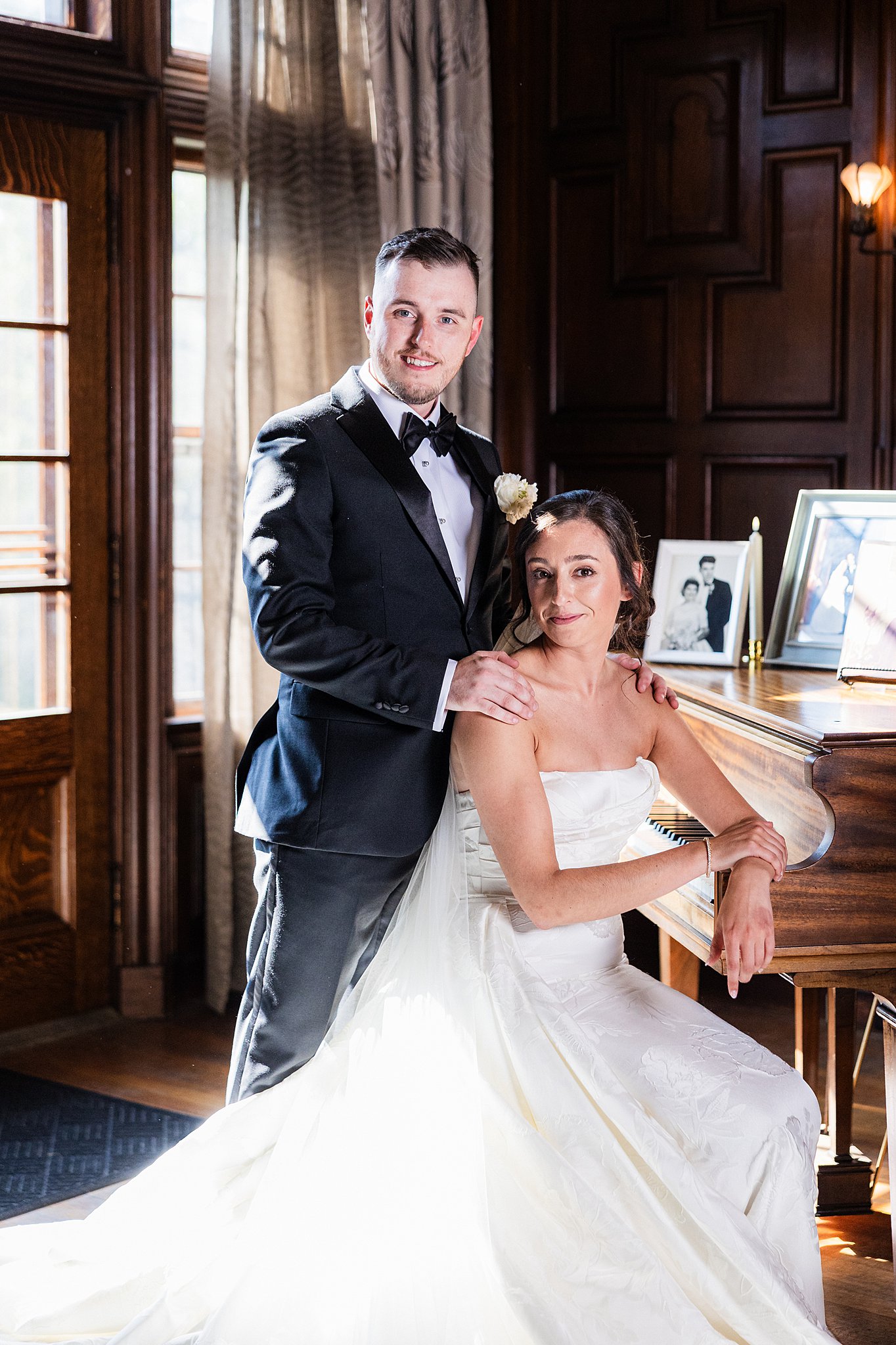 A bride and groom posing by a grand piano during a session with a Vermont wedding photographer.